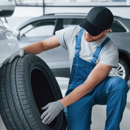Fresh material. Mechanic holding a tire at the repair garage. Replacement of winter and summer tires.