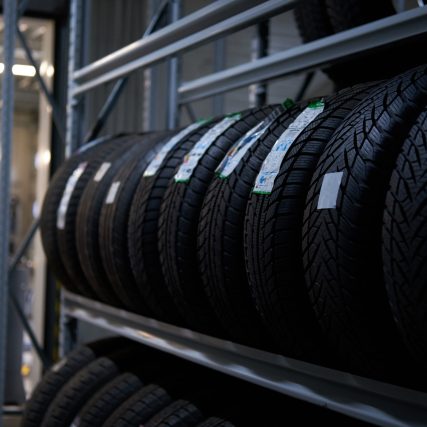 Brand new big variety of car's tyres on shelf with prices at store or warehouse.